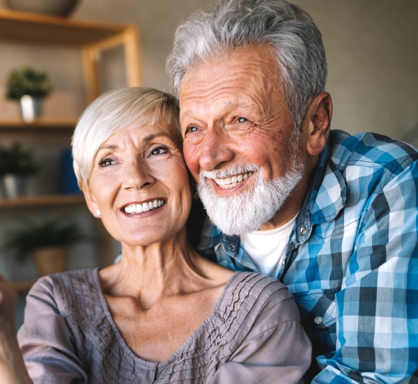 Older man and woman smiling after periodontal services