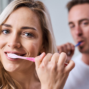 A woman and her husband brushing their teeth together