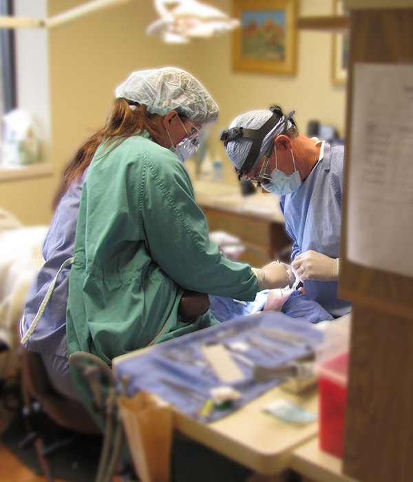 Periodontist and dental team members treating periodontal patient