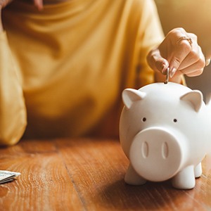 Someone putting a coin in a piggy bank