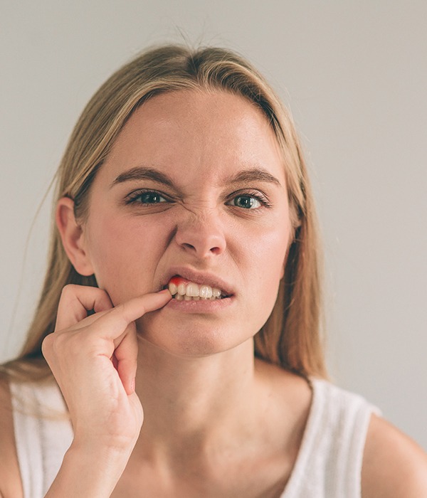 Woman with gum disease pointing to inflamed gums