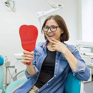 Smiling young woman admiring her new dental implants in Colorado Springs