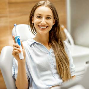 Woman holding toothbrush for dental implant care in Colorado Springs