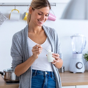 Woman smiling while eating jaw of yogurt
