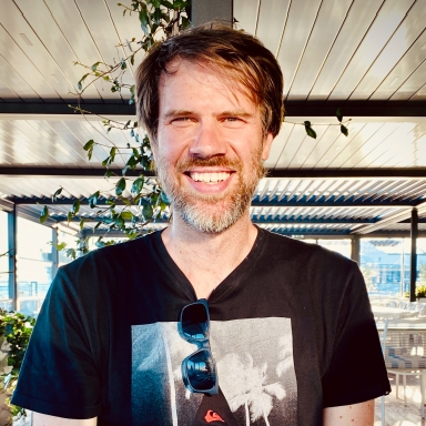 Man in black T shirt smiling outdoors