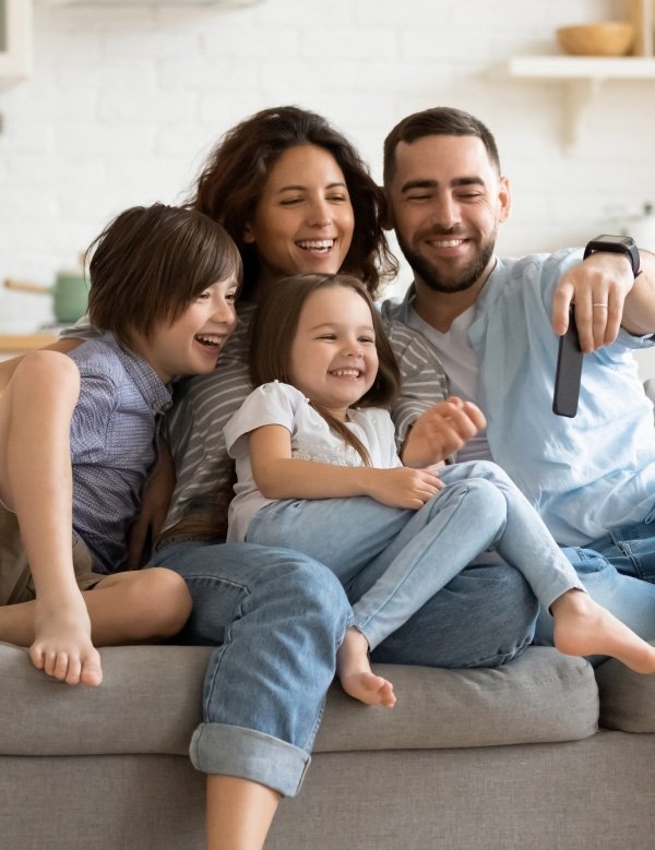 Smiling family of four sitting on couch looking at a cellphone