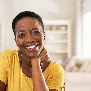 Woman in yellow shirt smiling while relaxing at home