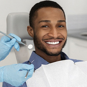 Man smiling during his dental appointment while wearing collared shirt