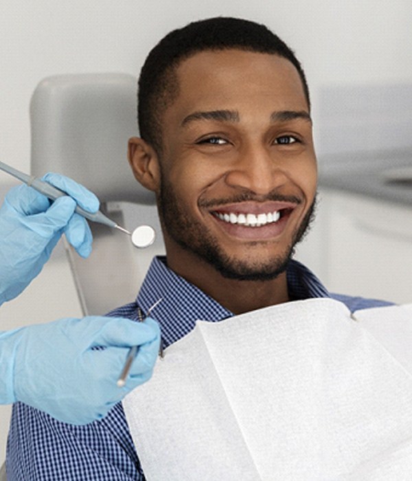Man smiling during his dental appointment while wearing collared shirt