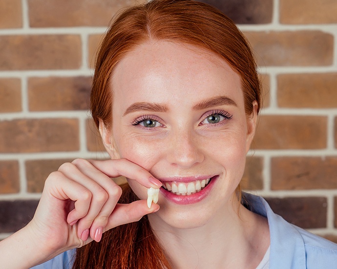 Woman holding up tooth after surgical extraction