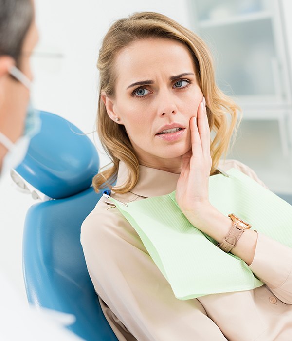 Woman in need of wisdom tooth removal holding jaw in pain