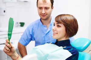 woman in dental chair looking at her smile after gum graft in Colorado Springs