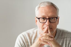 Man in glasses thinking with fingers crossed on his mouth