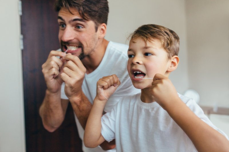 Father and son flossing to prevent gum disease