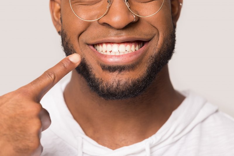 Man pointing at his mouth after receiving crown lengthening treatment