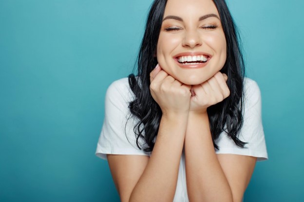 Woman smiling after receiving gum recontouring to correct her receding gums.