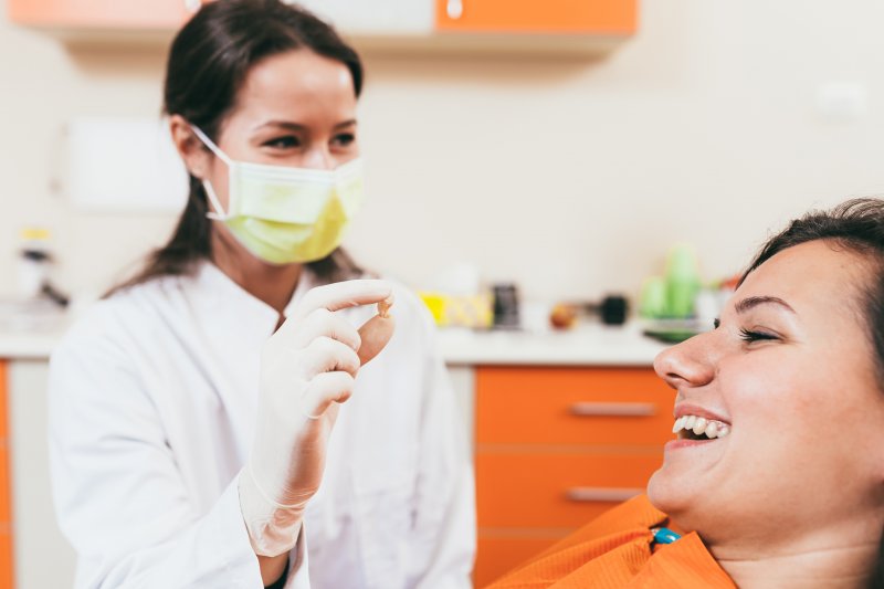 A dentist showing her patient her tooth after extraction